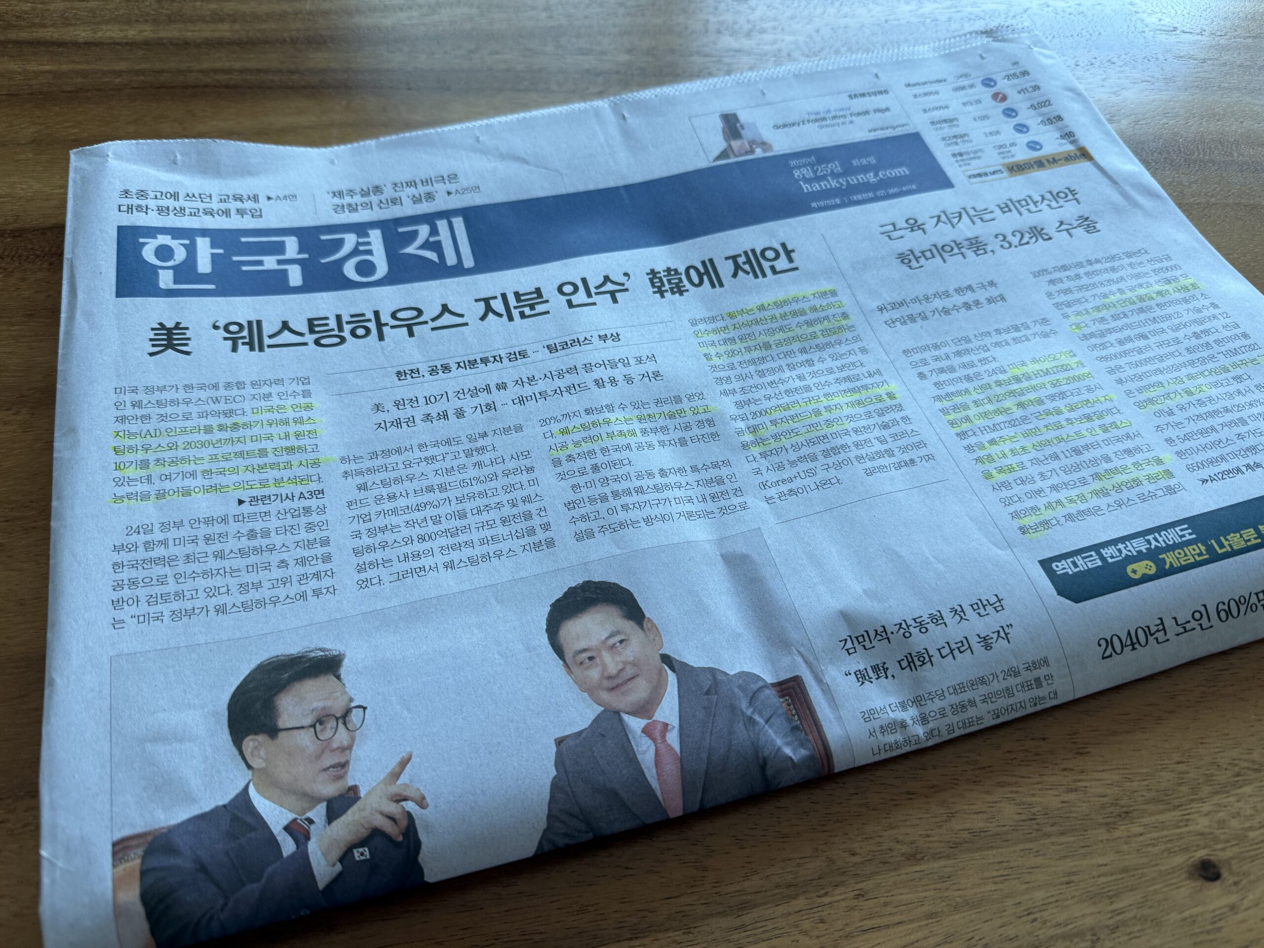 나무 책상 위에 펼쳐 둔 한국경제신문 1면. 머리기사는 '美 웨스팅하우스 지분 인수 韓에 제안'이고 오른쪽 기사 여러 곳에 형광펜이 그어져 있다. 아래에는 마주 앉아 대화하는 두 정치인의 사진이 나란히 실려 있다.