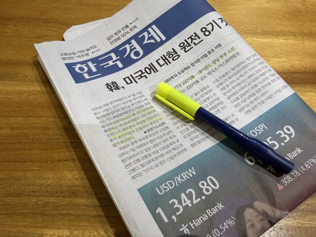 원목 식탁 위에 접어 둔 한국경제신문 1면, 그 위에 뚜껑을 연 노란 형광펜과 볼펜이 놓여 있다. 머리기사는 '韓, 미국에 대형 원전 8기'이고 오른쪽 아래에는 은행 전광판의 원·달러 환율이 찍힌 사진이 함께 실려 있다.